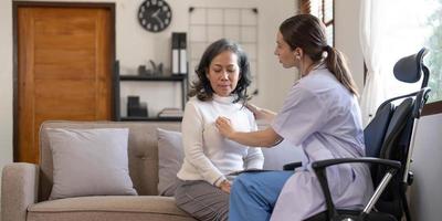 Asian female patient undergoing health check up while female doctor uses stethoscope to check heart rate in nurse, health care concept photo