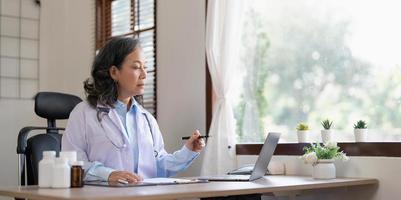 Confident female doctor sitting at office desk, health care and prevention concept. Portrait of friendly physician woman. Medicine concept. Portrait Of Smiling Female Doctor photo