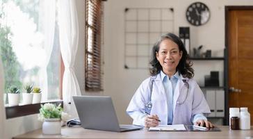 una doctora segura de sí misma sentada en el escritorio de la oficina, atención médica y concepto de prevención. retrato de una mujer médica amigable. concepto de medicina. retrato de una doctora sonriente foto