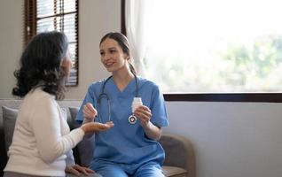 enfermera asiática que muestra el informe de control de salud a la abuela y da consejos. vida asistida médica visita al paciente mayor en casa. concepto de enfermería domiciliaria y cuidador de la salud foto