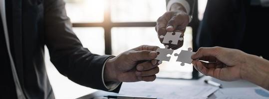 A group of business people assembling jigsaw puzzle. The concept of cooperation, teamwork, help and support in business. photo
