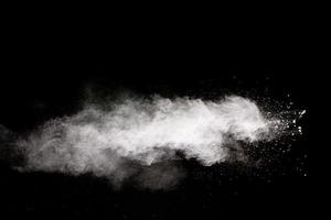 White powder explosion cloud against black background.White dust particle splash. photo