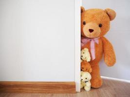 Background for children. The teddy bear family is standing behind the wall. photo