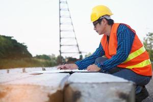 Engineers are reading the blueprint that is placed on piles in the construction area and the back has cranes. Building contractor concept photo