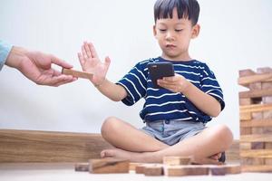 niños asiáticos en la era de las redes sociales que se enfocan en teléfonos o tabletas. concepto de niños adictos a los videojuegos foto