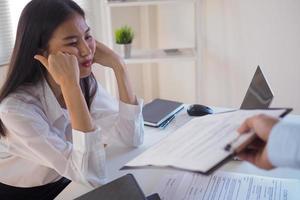 Young women working at the office are bored, looking at the documents submitted by them. photo