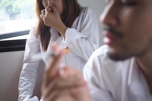 Men are smoking and women close their noses. Smoking in public places photo