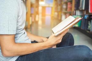 vista lateral de un estudiante masculino leyendo libros en la biblioteca. foto