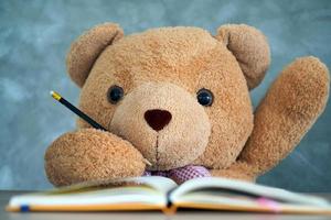 oso de peluche sentado en un escritorio y levante la mano cuando se le pregunte. comunicación a los escolares. dale a teddy bear un representante estudiantil foto