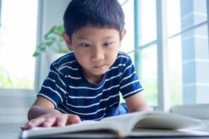 The little boy is reading a book in the house area. Learning at home photo