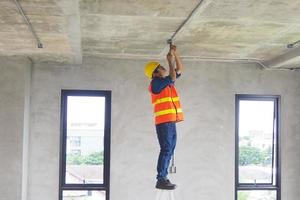 electricista que trabaja en la habitación los técnicos de mantenimiento instalan el cableado en el hogar. foto