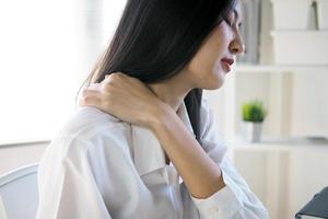 Asian women have neck and shoulder pain from sitting for a long time. photo