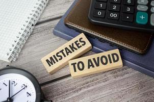 Mistakes To Avoid symbol. Concept words pay off debts on wooden blocks photo