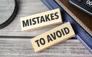 Mistakes To Avoid. text on wooden blocks on wooden background with office supplies photo