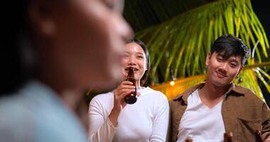 Footage of Happy Asian friends having dinner party together - Young people sitting at bar table toasting beer bottle dinner outdoor  - People, food, drink lifestyle, new year celebration concept. video