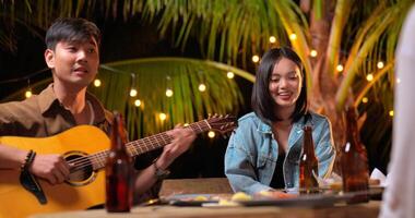 imágenes de feliz grupo asiático de amigos divirtiéndose con música cenando y bebiendo juntos al aire libre - grupo de amigos felices brindando cervezas - gente, comida, estilo de vida de bebida, concepto de celebración de año nuevo. video