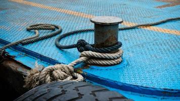 cuerda de barco atada a un gran bolardo de acero bitt en el puerto foto