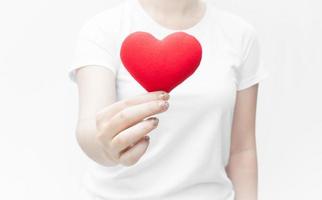 mujer sosteniendo y protegiendo una forma de corazón rojo en primer plano de fondo blanco, símbolo de amor o saliendo con el día de san valentín foto