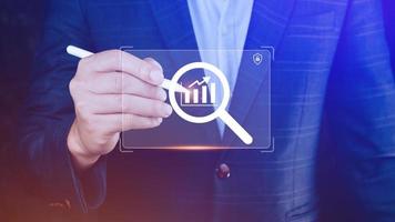 Businessman showing business growth on graph Hands touching graphs representing increasing profits with virtual interface technology, financial symbols coming photo