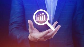 Businessman showing business growth on graph Hands touching graphs representing increasing profits with virtual interface technology, financial symbols coming photo
