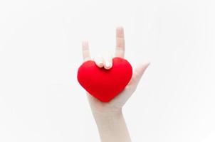 signo de amor por mano de mujer y forma de corazón rojo en primer plano de fondo blanco, símbolo de amor o fecha de San Valentín foto