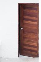 puerta de madera con marco y panel sobre fondo de pared blanca, imagen frontal de una puerta de madera abierta