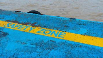 zona de seguridad de línea amarilla en el suelo junto al agua, fondo de metal oxidado antiguo, muelle de hierro con textura de metal oxidado de línea de zona de seguridad foto