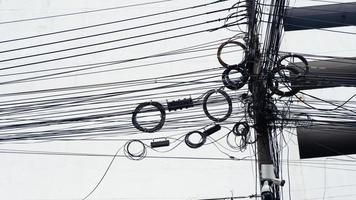 cables de línea de señal enredados en el poste de la línea caótica en el poste eléctrico en la calle peatonal, cable eléctrico enredado en la calle tailandesa foto