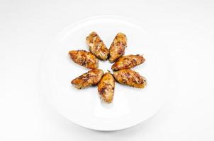 Grilled chicken wings in dish white on white background photo