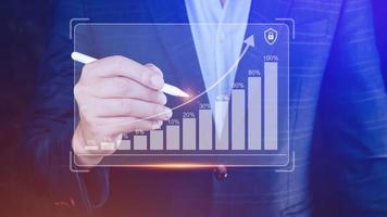 Businessman showing business growth on graph Hands touching graphs representing increasing profits with virtual interface technology, financial symbols coming photo