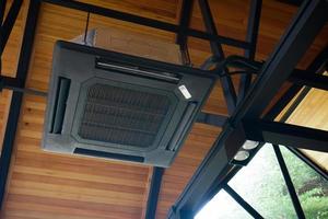 Big modern square black air conditioner attached to black steel frame under wooden ceiling photo