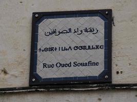 Small street sign tri lingual arabic french and berber in Fez medina old town. Morocco. photo
