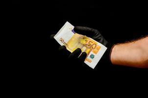 mano sujetando dinero en efectivo sobre fondo negro foto