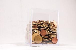 Coins in a container on white background photo