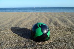 Green and black globe at the beach photo
