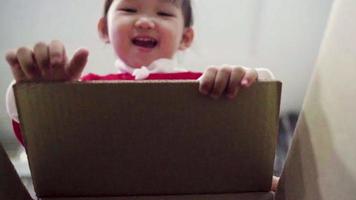 el niño abrió una caja con un regalo. camara lenta. una niña mira en la caja, está sorprendida y feliz de recibir una sorpresa. caja de navidad. feliz navidad. video