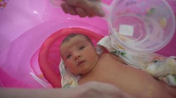 Newborn baby girl bathes in bathtub for first time video