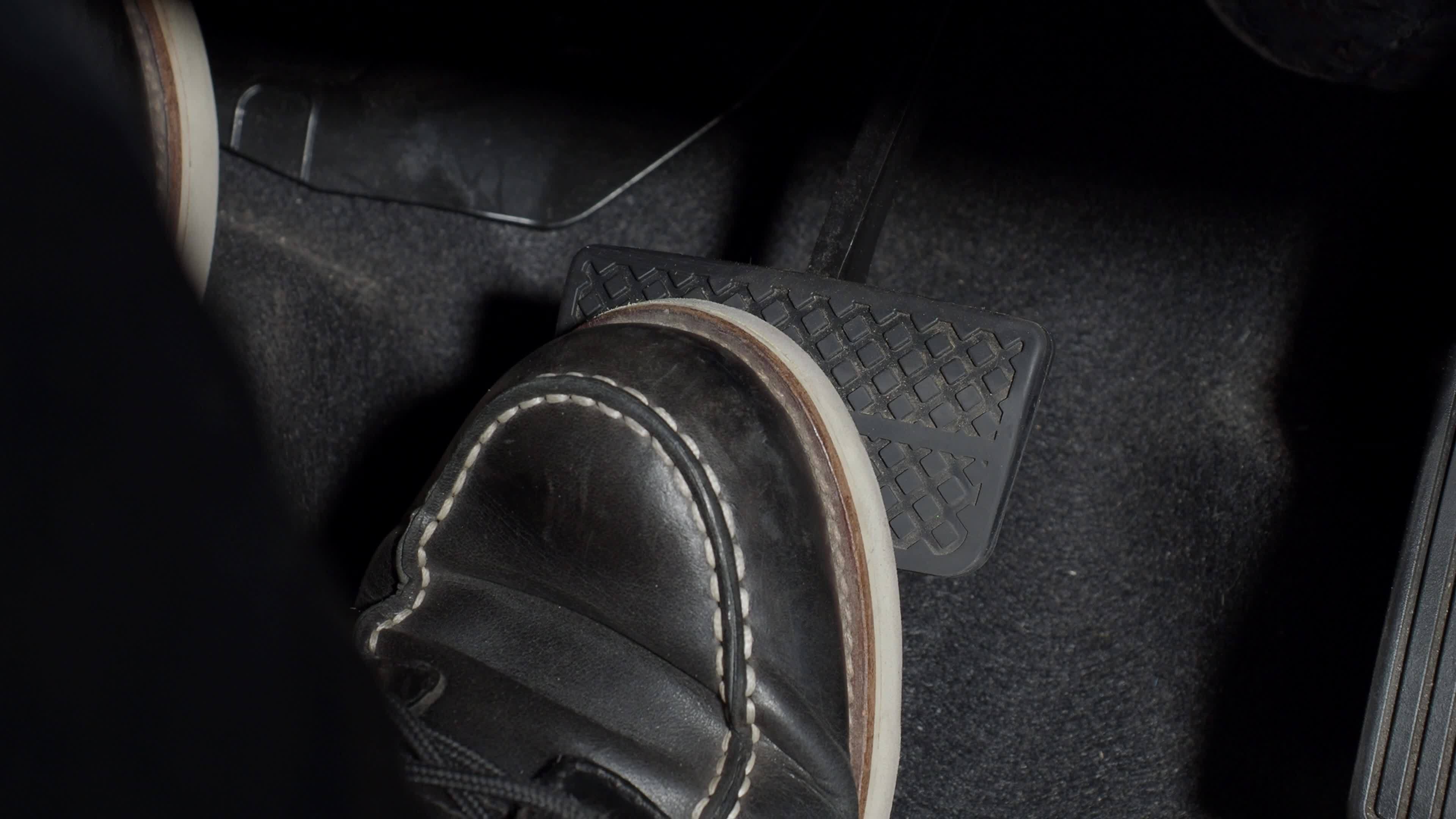 Accelerate and Brake. Foot pressing foot pedal of a car to drive ahead