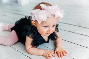 Little crawling baby girl one year old siting on floor in bright light living room smiling and laughing photo