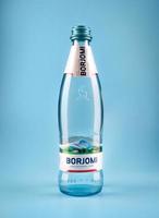 krasnoyarsk, rusia - 01 de noviembre de 2022 botella de agua mineral georgiana borjomi sobre un fondo azul. agua mineral en una botella de vidrio. foto