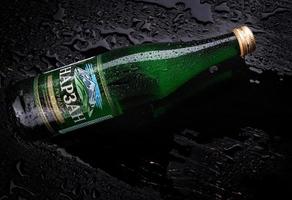 KRASNOYARSK, RUSSIA - NOVEMBER 01, 2022  A bottle of misted NARZAN mineral water on a black wet surface. photo