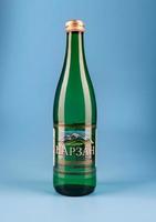 KRASNOYARSK, RUSSIA - NOVEMBER 01, 2022 Bottle of mineral water NARZAN on a blue background. Mineral water in a glass bottle. photo