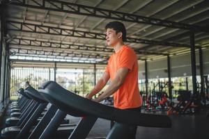 Asian men are happy jogging and running on a treadmill at gym. A man is jogging and doing cardio training. Healthy lifestyle concept. Doing exercise for longer life photo