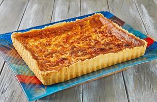 Tart with potatoes and cheese on glass plate on wooden background photo