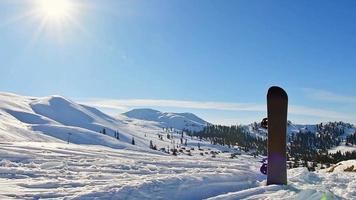 stand de snowboard en la nieve con hermoso fondo blanco de las montañas del cáucaso en el punto de vista superior de la estación de esquí de gudauri en invierno. destino de vacaciones de invierno para esquiar en georgia video