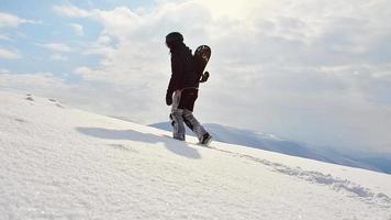 Snowboarder walking with snowboard during sunset in the snowy mountains. Cinematic solo freerider snowboarder background video