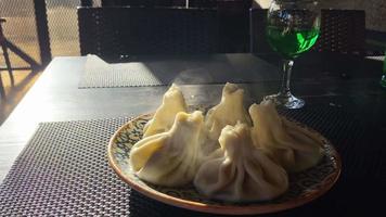 Traditional Georgian dish, khinkali Kalakuri, on a wooden table served with green with Tarkhun georgian limonade video