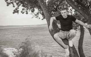Young male model sitting on tree landscape Novi Vinodolski Croatia. photo