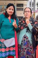 New Delhi, India - December 04 2022 - Unidentified people showing their ink-marked fingers after casting votes in front of polling booth of east Delhi area for MCD local body Elections 2022 photo