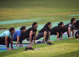 New Delhi, India, June 18 2022 - Group Yoga exercise class Surya Namaskar for people of different age in Lodhi Garden, International Yoga Day, Big group of adults attending a yoga class in park photo